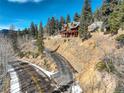 Scenic driveway leading to a beautiful cabin-style home surrounded by lush trees and natural landscape at 11450 Marks Dr, Conifer, CO 80433