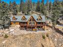 Stunning exterior elevation of a log cabin home with multiple decks, a hot tub, and views of mature trees at 11450 Marks Dr, Conifer, CO 80433
