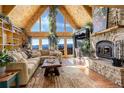 Cozy living room boasts vaulted wood ceilings, a stone fireplace, large windows, and scenic mountain views at 11450 Marks Dr, Conifer, CO 80433