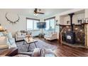 Cozy living room with hardwood floors, stone fireplace, large windows offering picturesque views, and stylish decor at 11932 Coal Creek Heights Dr, Golden, CO 80403
