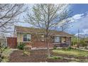 Quaint brick home featuring neat landscaping with mulch, greenery, and a welcoming bench on the lawn at 3600 Olive St, Denver, CO 80207
