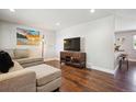 Cozy living room with hardwood floors, neutral walls, comfortable sectional couch, and entertainment center at 3145 W Farmdale Rd, Englewood, CO 80110