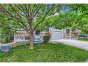 Charming home with covered porch, seating area, stone accents, manicured lawn, and mature trees at 12125 Helena St, Brighton, CO 80603