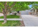 Charming home with gray siding, stone accents, mature trees, and a two car garage at 12125 Helena St, Brighton, CO 80603