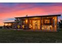 Home exterior at dusk with open porch, stone accents, and outdoor seating at 11881 County Road 37, Fort Lupton, CO 80621