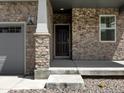 Inviting entrance with a stone facade, a sturdy front door, and a well-lit porch for added security at 546 Red Rock Pl, Brighton, CO 80601