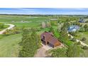 Overhead view of a cozy home with an attached garage, bordered by tall trees and sprawling green lawns at 3163 Windstream Ln, Elizabeth, CO 80107