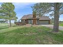 Inviting home with a deck and a well-manicured lawn, accented by mature trees, enhancing its curb appeal at 3163 Windstream Ln, Elizabeth, CO 80107