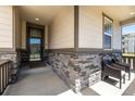 Inviting covered front porch, adorned with stone detailing and comfortable seating at 10595 Boston St, Commerce City, CO 80640
