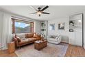 Bright living room featuring a leather couch, a ceiling fan, and built-in shelves at 12017 W 58Th Pl, Arvada, CO 80004