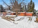 View of a single-story home featuring a wooden facade, attached garage, and large mature trees in a snow covered yard at 1333 Mariposa Ave, Boulder, CO 80302