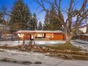 Charming exterior of a single-story home featuring a wooden facade, stone walkway, and mature trees in a snow covered yard at 1333 Mariposa Ave, Boulder, CO 80302