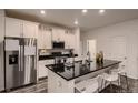 Modern kitchen with stainless steel appliances, black countertops, and white cabinetry at 21538 E 59Th Pl, Aurora, CO 80019