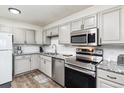 Close up of updated kitchen featuring granite countertops, stainless appliances and gray cabinets at 300 S Clinton St # 8C, Denver, CO 80247