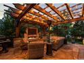 Inviting outdoor patio featuring a stone fireplace, comfortable seating, and a pergola with string lights at 6122 Maroon Peak Pl, Castle Rock, CO 80108