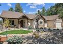 Inviting home exterior featuring stone accents, a covered porch, and meticulous landscaping at 1151 Kenosha Dr, Larkspur, CO 80118