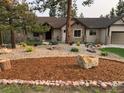Landscaped front yard with natural rock features and mulched garden beds at 1151 Kenosha Dr, Larkspur, CO 80118