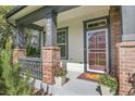 Inviting front porch with brick columns, potted plants, and a welcome mat at 8056 E 35Th Ave, Denver, CO 80238