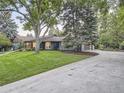 An exterior view of the home with a spacious front yard and long driveway leading to a garage at 3961 S Clermont St, Cherry Hills Village, CO 80113