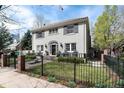 Two-story gray home with a black gated fence, front porch with seating, and landscaped garden at 121 N Marion St, Denver, CO 80218