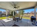 Relaxing covered patio with fan, dining set, and a view of the spacious backyard and greenery at 551 Rio Rancho Way, Brighton, CO 80601