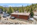 Rear exterior of charming log cabin with hot tub, patio furniture and scenic views of mountains and evergreens at 764 Blue Ridge Rd, Breckenridge, CO 80424