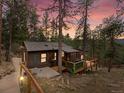 Secluded cabin featuring wood siding and deck, surrounded by trees with a sunset backdrop at 4786 Forest Hill Rd, Evergreen, CO 80439