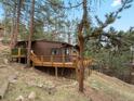 Wood cabin featuring an expansive wooden deck overlooking a sloped yard among the trees at 4786 Forest Hill Rd, Evergreen, CO 80439