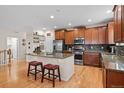 Open kitchen featuring a large island with seating, stainless appliances, wood cabinets, and hardwood floors at 15271 Grasslands Dr, Parker, CO 80134