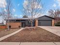 Charming home with brick and gray siding, a well-manicured lawn, and a two-car garage, enhanced by a bright blue sky backdrop at 2723 S Knoxville Way, Denver, CO 80227