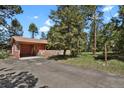 A single-Gathering home featuring a spacious driveway, lush lawn, and beautiful natural surroundings at 9359 Barnes Ave, Conifer, CO 80433