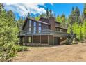 Exterior view of home featuring a large wraparound deck, garage, and mature trees at 11333 Conifer Mountain Rd, Conifer, CO 80433