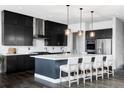 A gourmet kitchen with dark cabinetry, a large island, stainless steel appliances, and designer pendant lighting at 9388 E 59Th Pl, Denver, CO 80238