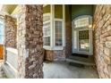 Inviting front porch with brick pillars, arched doorway, and decorative front door with glass detail at 1588 W 111Th Ave, Northglenn, CO 80234