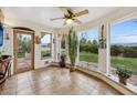 Bright sun room with tiled flooring, ceiling fan, large windows offering mountain views, and door to patio at 1069 Crestmoor Dr, Boulder, CO 80303