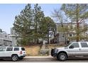 A street view of the townhome complex with mature trees and parking in front at 46 S Nome St, Aurora, CO 80012