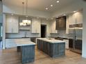 Modern kitchen boasts white cabinets, wood accents, stainless steel appliances, and marble countertops with two islands at 5841 Powell Rd, Parker, CO 80134