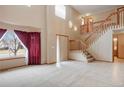 Open living room featuring high ceilings, a staircase, large windows, and neutral tones at 5596 S Urban St, Littleton, CO 80127