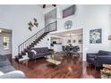 Elegant living room featuring vaulted ceilings, hardwood floors, and an open staircase leading to the upper level at 14120 E Warren Pl, Aurora, CO 80014