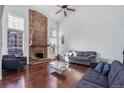 Spacious living room with a large brick fireplace, hardwood floors, and plenty of natural light from the oversized windows at 14120 E Warren Pl, Aurora, CO 80014