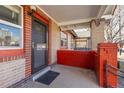 Covered front porch with brick columns and black front door on a charming home at 1556 Osceola St, Denver, CO 80204