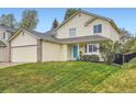 Lovely two-story home with yellow siding, attached garage, a well-kept lawn, and a bright blue front door at 4349 S Genoa Ct, Centennial, CO 80015