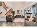 Bright living room featuring hardwood floors, neutral walls, a fireplace, comfortable furniture, and a wooden staircase at 4349 S Genoa Ct, Centennial, CO 80015