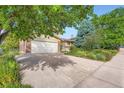 Two-story house with an attached garage, and a spacious driveway, surrounded by mature trees and lush landscaping at 13934 W Warren Dr, Lakewood, CO 80228