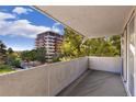 Balcony view of surrounding city buildings and green trees with a concrete wall and sliding glass doors at 740 N Pearl St # 203, Denver, CO 80203