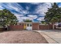 Street view of a brick ranch-style house with a sunny yellow door and neat, low-maintenance landscaping at 1906 S Vrain St, Denver, CO 80219