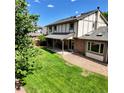 Backyard featuring a covered patio, well-manicured lawn, mature trees, and a gravel border, creating a serene outdoor space at 16639 E Berry Ln, Centennial, CO 80015