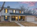 Charming two-story home featuring a brick facade, covered porch with seating area, and attached garage at 11861 E Yale Ct, Aurora, CO 80014