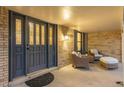 Inviting covered front porch with seating area, brick accents, and decorative front door with leaded glass at 11861 E Yale Ct, Aurora, CO 80014
