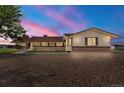 Dusk view of the ranch-style home featuring a brick facade, covered porch and a gravel driveway at 1851 E 138Th Ave, Brighton, CO 80602